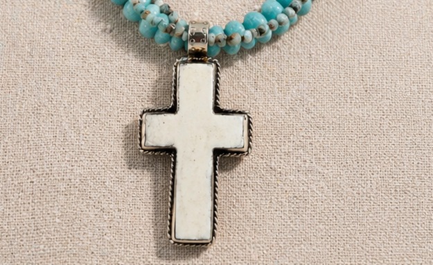Hand-carved bone cross pendant detail on artisan necklace