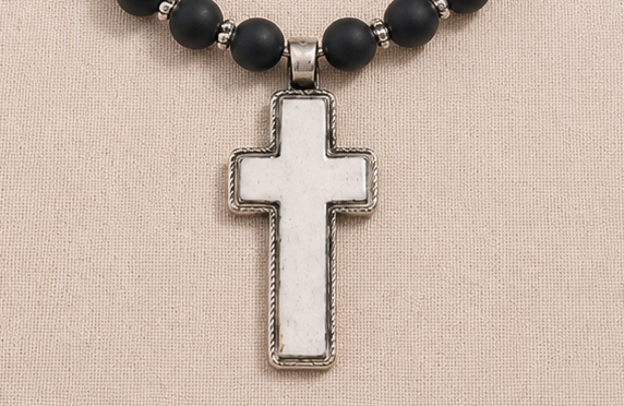 Hand-carved bone cross pendant detail on artisan necklace