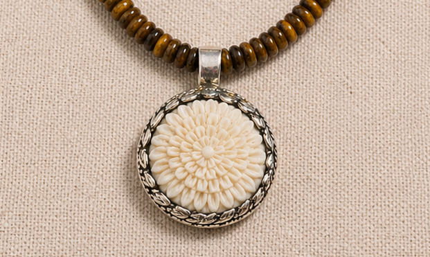 Hand-carved bone flower pendant detail on artisan necklace