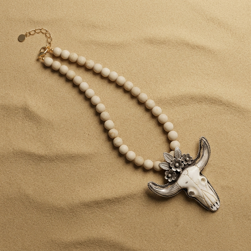 Desert Prairie Longhorn Necklace with faceted river stone beads and carved bone longhorn pendant on sand background