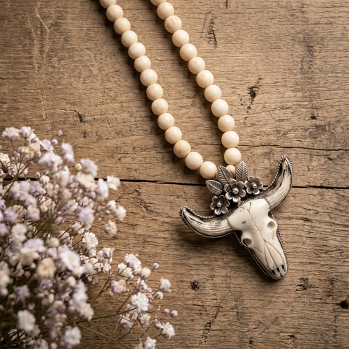Desert Prairie Longhorn Necklace with faceted river stone beads and carved bone longhorn pendant on sand background