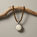 High Desert Tiger’s Eye Necklace with brown and gold tiger’s eye beads and carved bone flower pendant on linen background