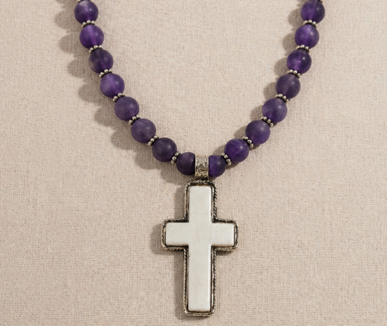 Mesa Amethyst Necklace with purple amethyst beads and bone cross pendant on linen background