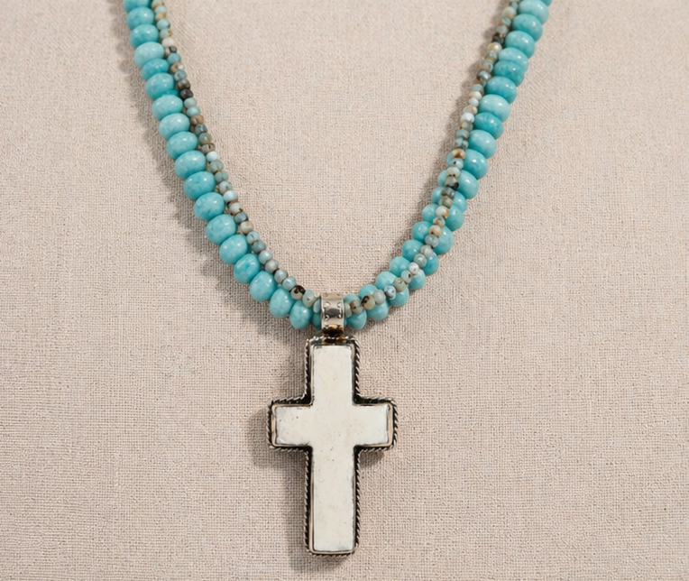 Mesa Ocean Multi-Strand Necklace with amazonite and larimar beads and bone cross pendant on linen background
