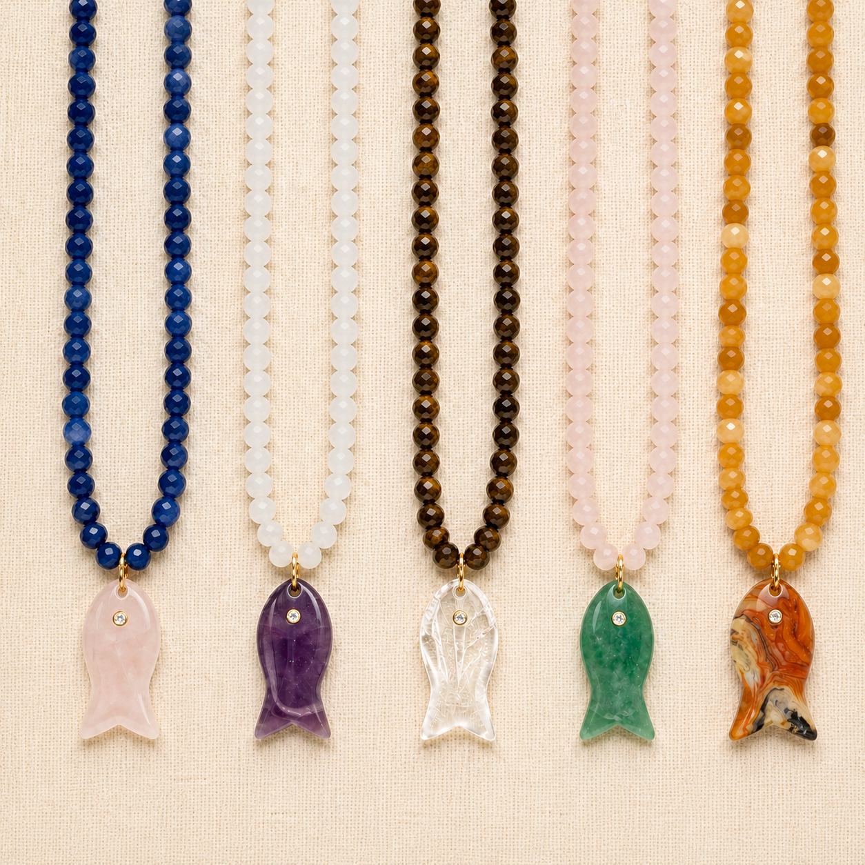 Salt and Stone Necklace collection with gemstone fish pendants on linen background