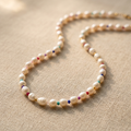 Pearl necklace with colorful beads on a beige fabric background