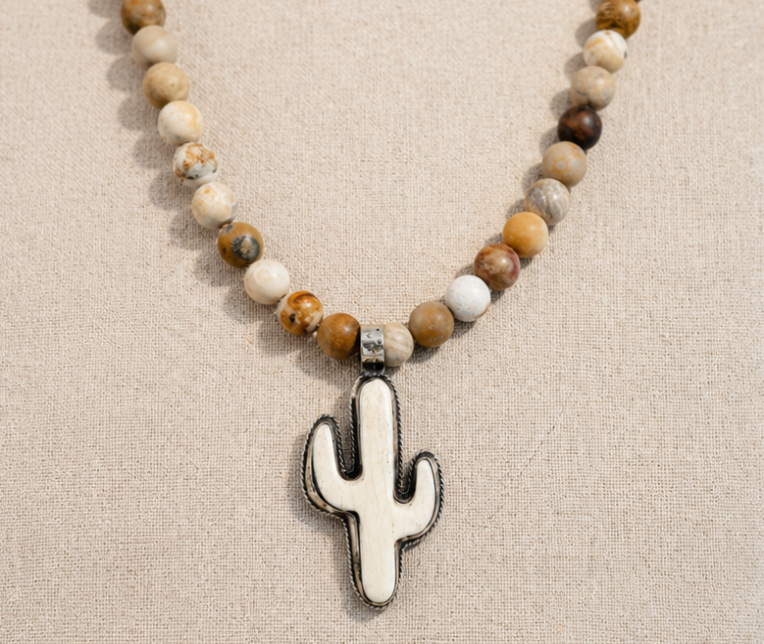 Sundown Fossil Necklace with fossil coral beads and bone cactus pendant on linen background